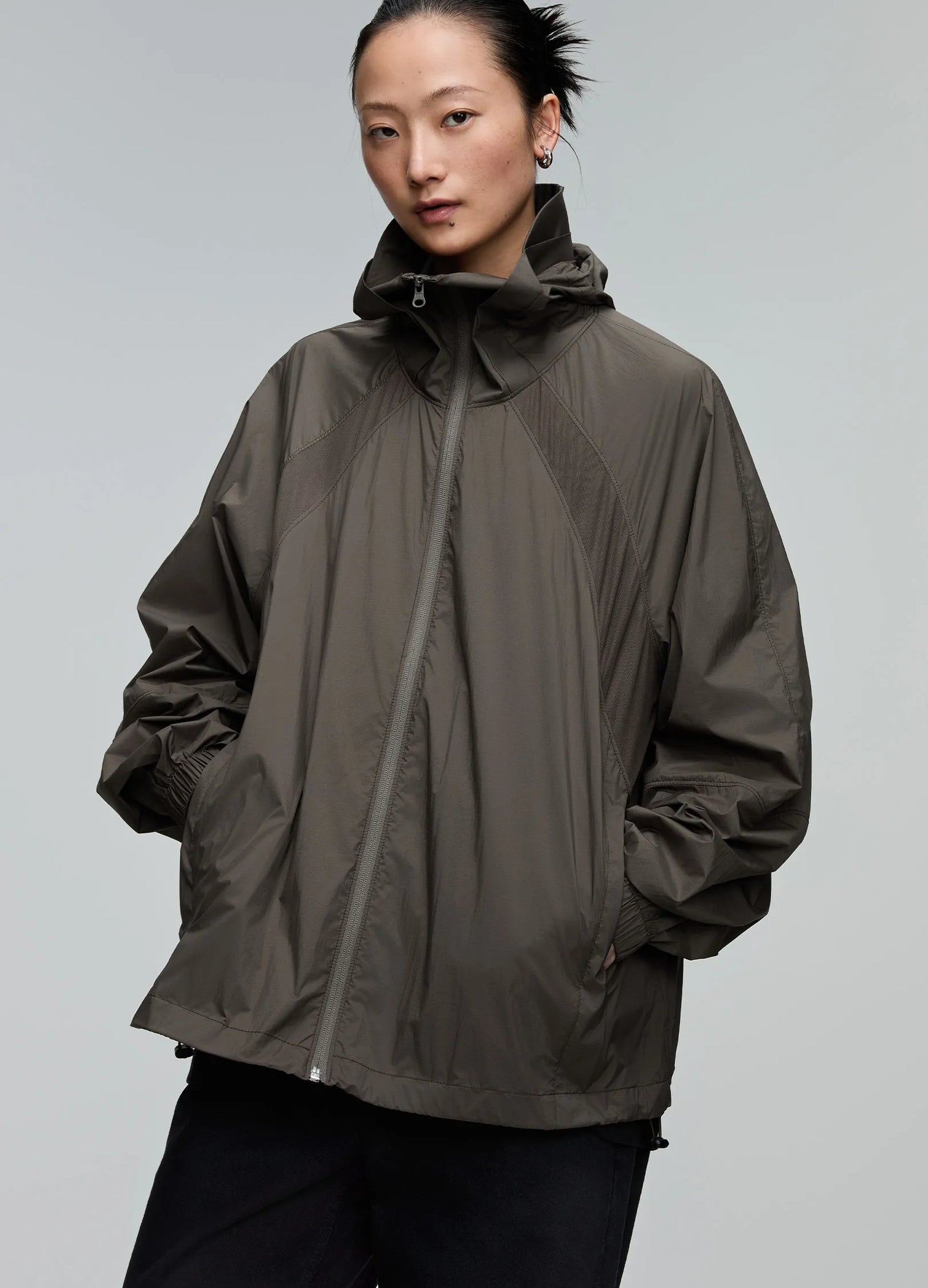 Person wearing a brown raincoat against a gray background