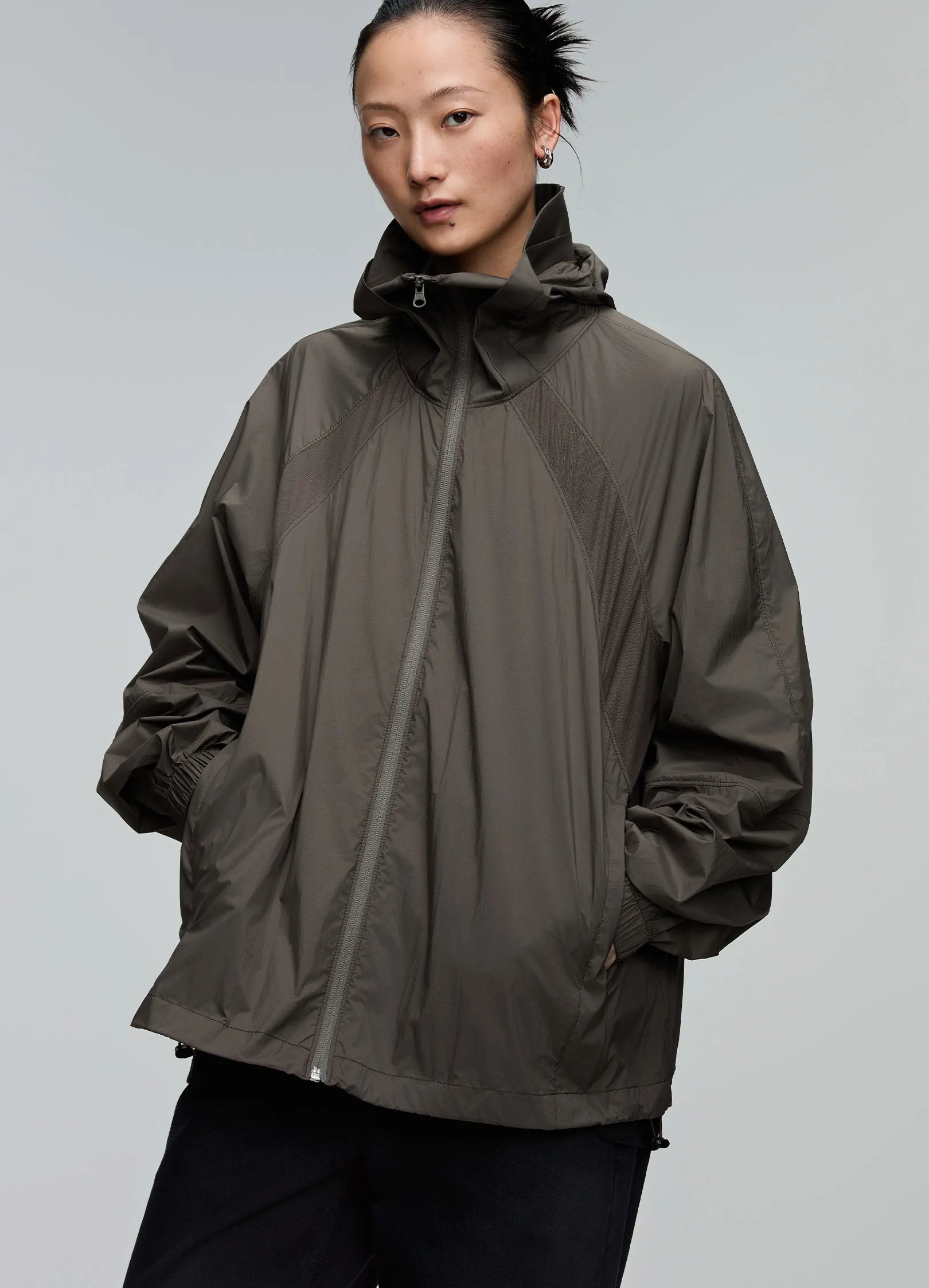Person wearing a brown raincoat against a gray background